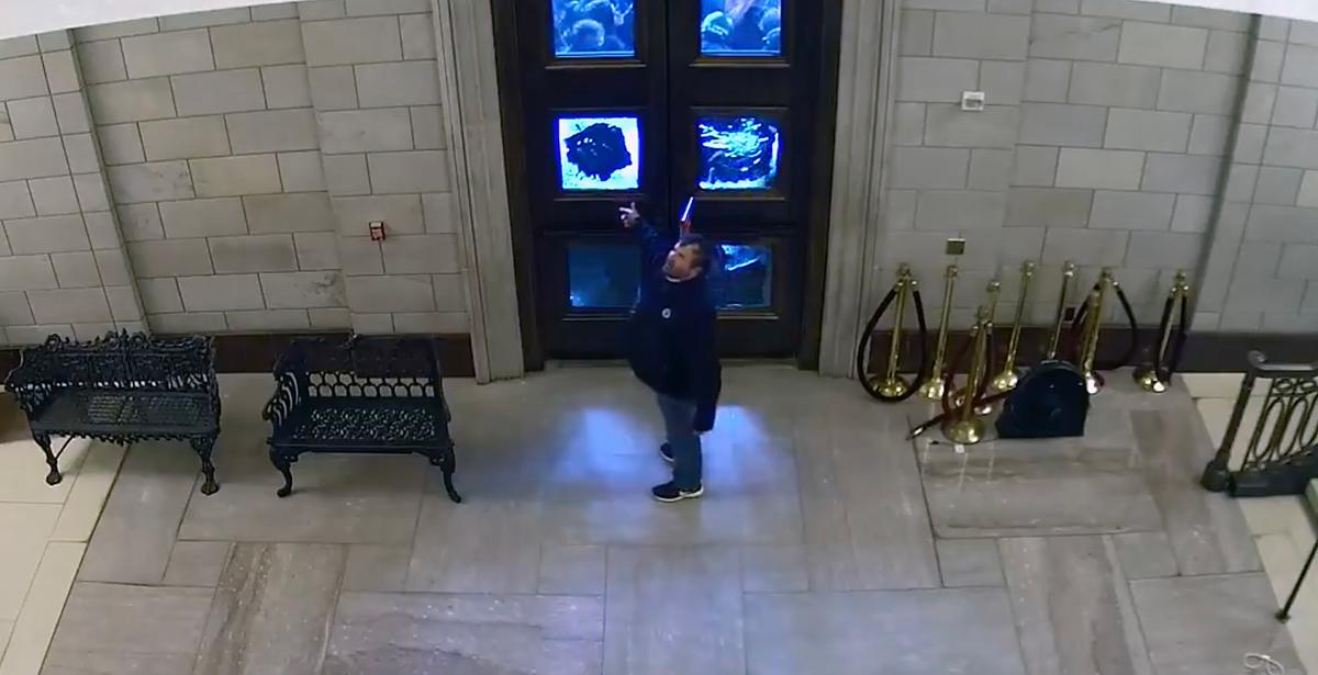 A protester appears to be listening to instructions shortly before he deactivates the lock on the inner Columbus Doors at the U.S. Capitol on Jan. 6, 2021. Defendants charged with breaching the doors argue this CCTV video shows the doors were opened from the inside. (Video Still/U.S. Department of Justice)
