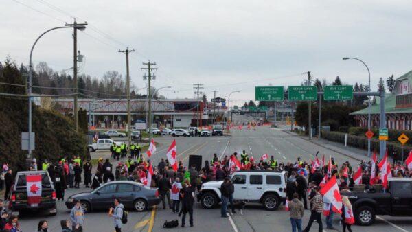 Protesters rally near the Pacific Highway border crossing while police keep watch, in Surrey, B.C., on Feb. 13, 2022. (Chris Ivany)