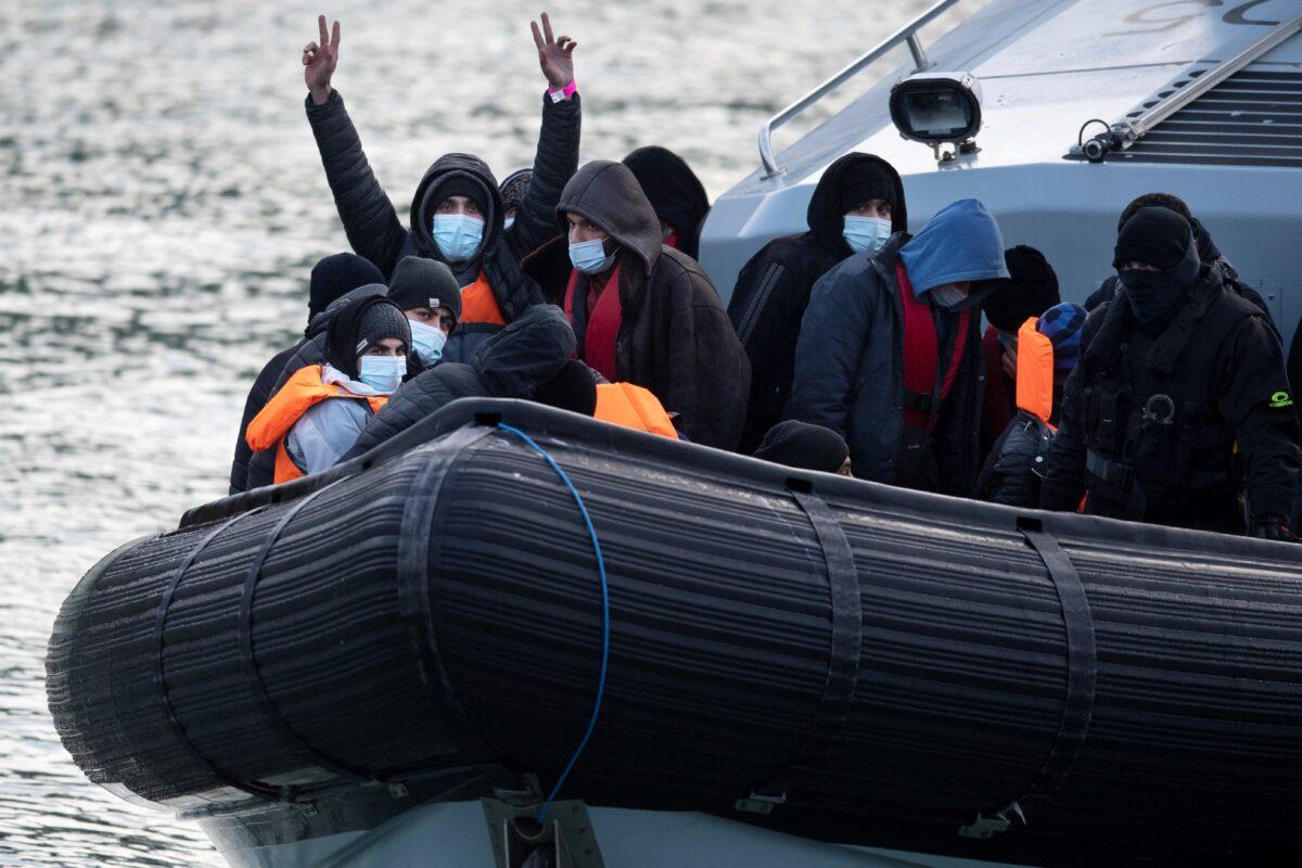 Illegal immigrants react onboard a UK Border Force vessel HMC Speedwell after being picked up at sea, as they're brought into the Marina in Dover, England, on Dec. 21, 2021. (Ben Stansall/AFP via Getty Images)