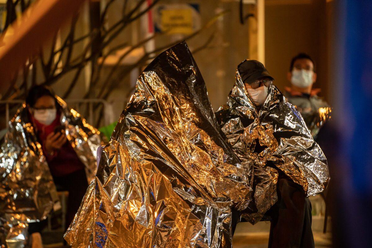 Patients wrapping in emergency thermal blankets wait at a temporary holding area outside Caritas Medical Centre in Hong Kong on Feb. 16, 2022. (Anthony Kwan/Getty Images)