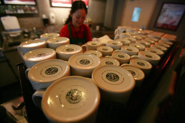 An employee behind a shelf of up-turned mugs in a Starbucks coffee shop in Chongqing, China on Dec. 18, 2007. (China Photos/Getty Images)