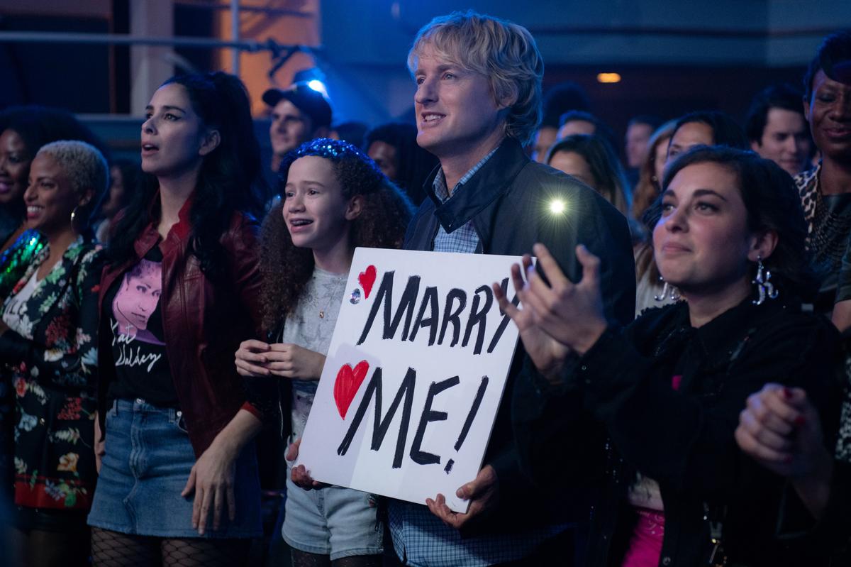 Parker (Sarah Silverman, second from left), Lou (Chloe Coleman), and Charlie (Owen Wilson) attend the hugely public wedding of a pop star, in “Marry Me.” (Barry Wetcher/Universal Pictures)