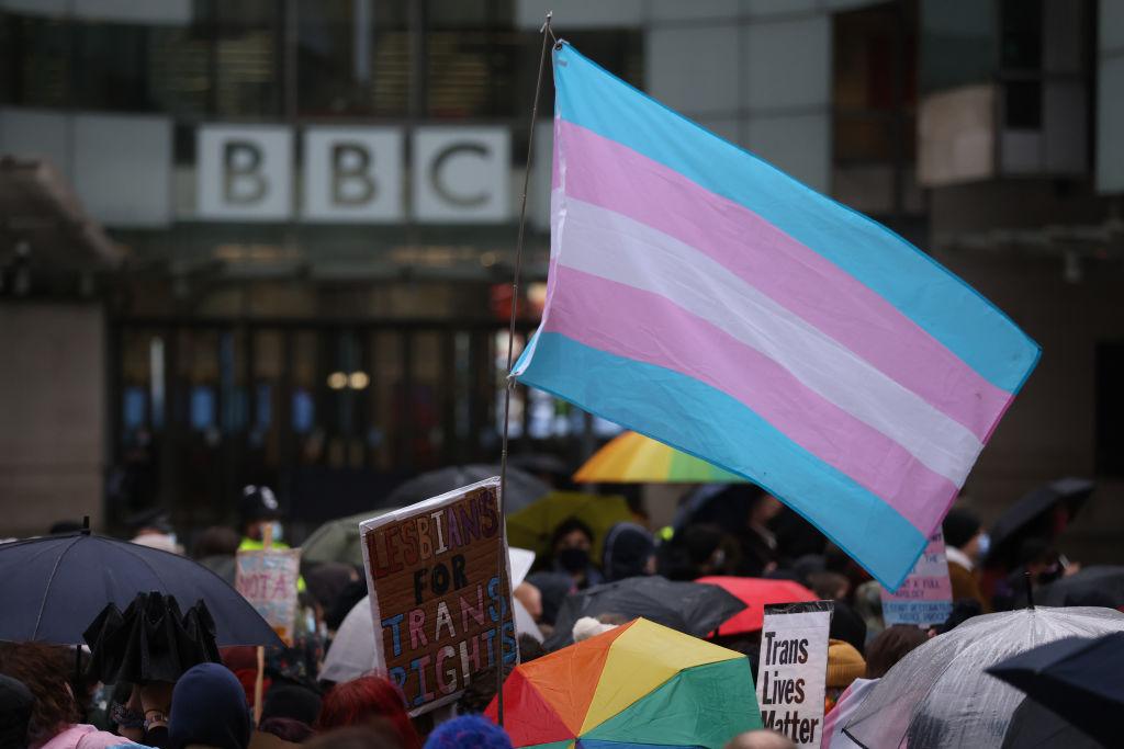 Demonstrators hold placards and wave a transgender pride flag during the Trans Activism UK "British Bigotry Corporation: Platforming Hate Is Not Impartial" protest at BBC Broadcasting House in London on January. 8, 2022. (Hollie Adams/Getty Images)
