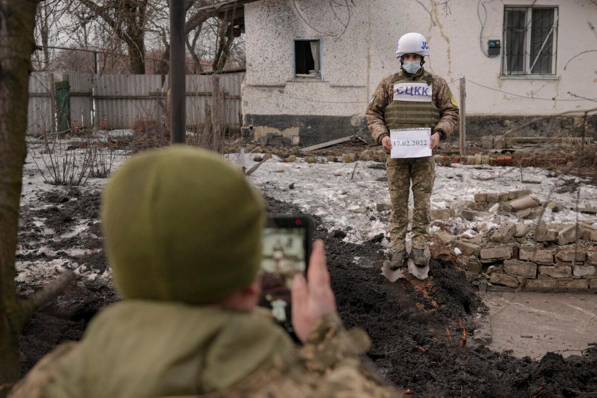 Members of the Joint Centre for Control and Coordination on ceasefire of the demarcation line, or JCCC, take forensic photos of damage to a house from an artillery shell that landed in Vrubivka, in the Luhansk region of eastern Ukraine, on Feb. 17, 2022. (AP Photo/Vadim Ghirda