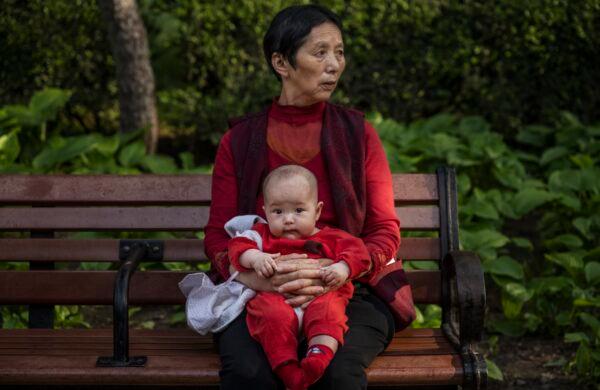 A woman holds a baby at a park in Beijing, China on May 12, 2021. (Kevin Frayer/Getty Images)