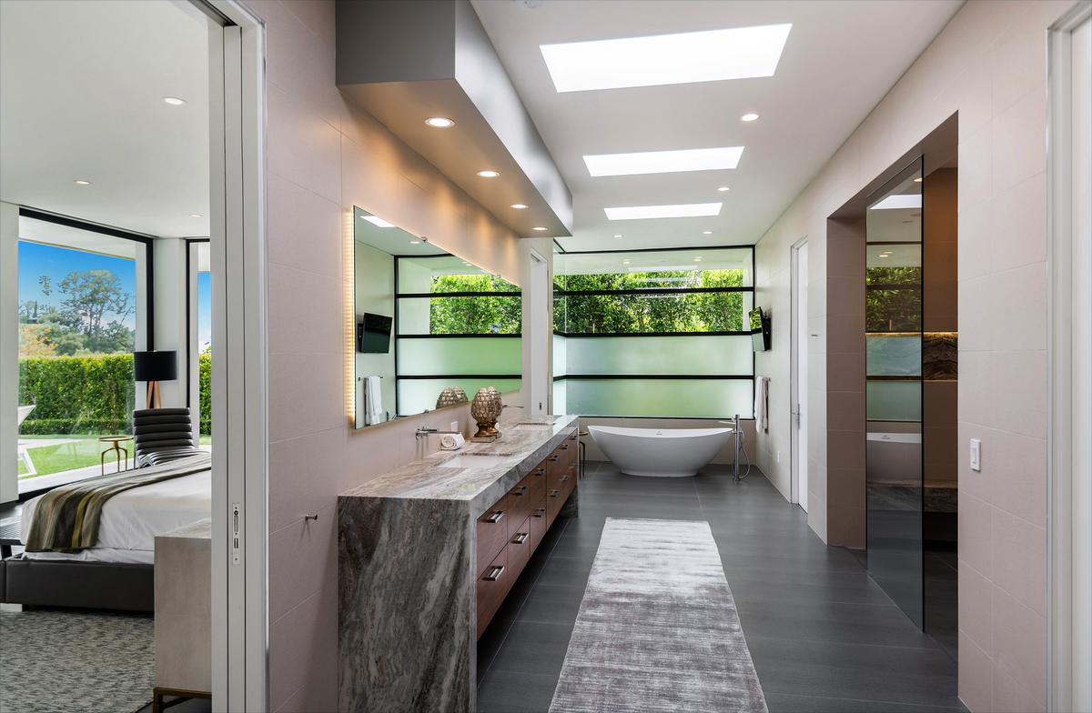 The careful selection of materials makes the crisp contemporary design more welcoming. The modern coolness of the house is toned down delicately by ambient light and access to the lush nature that surrounds the home. (Courtesy of Jade Mills Estates)