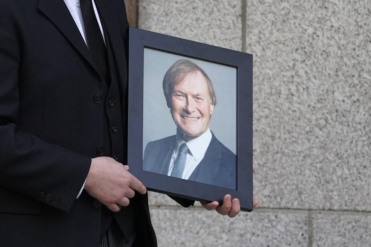A photograph of Sir David Amess is held by a mourner in an undated file photo. (Kirsty O’Connor/PA)