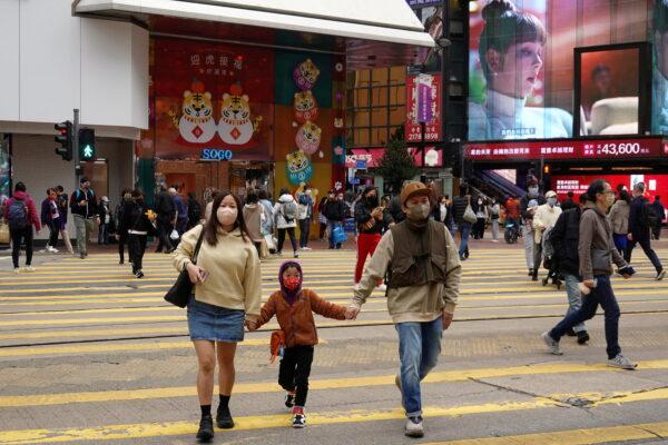 Pedestrians cross a street at Causeway Bay district in Hong Kong on Feb. 9, 2022. (Joyce Zhou/Reuters)