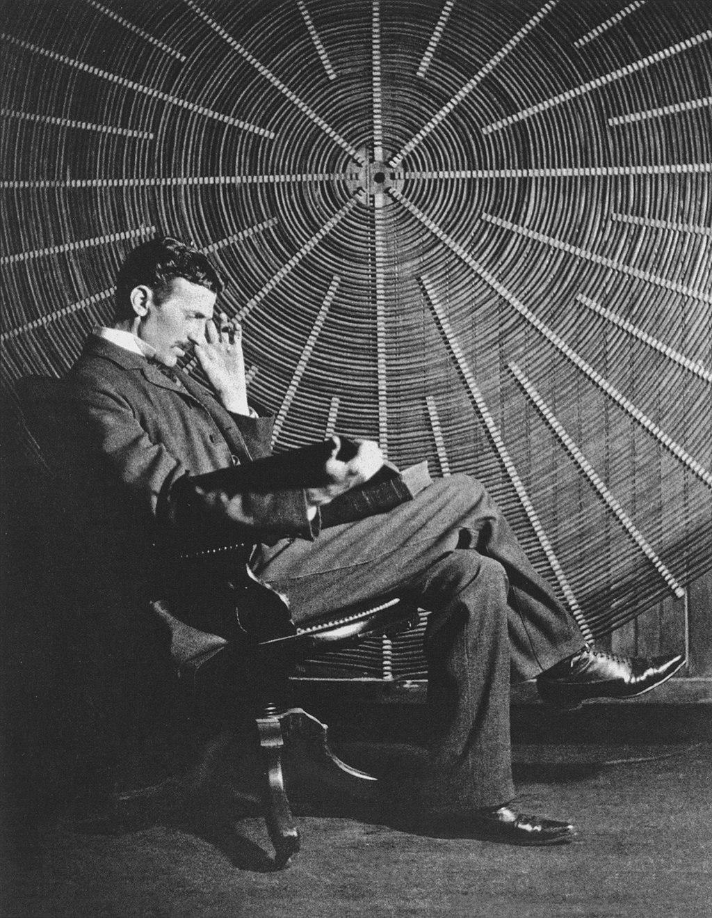 Nikola Tesla sitting in front of a spiral coil used in his wireless power experiments at his East Houston St. laboratory in New York. (Public Domain)