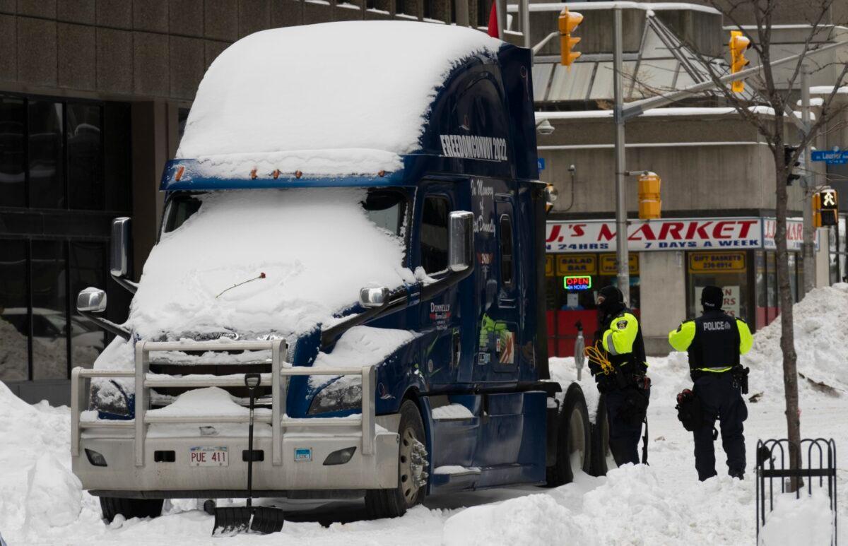 Police inspect one of the few remaining protest trucks before having it towed out of the downtown core, in Ottawa on Feb. 20, 2022. (The Canadian Press/Adrian Wyld)