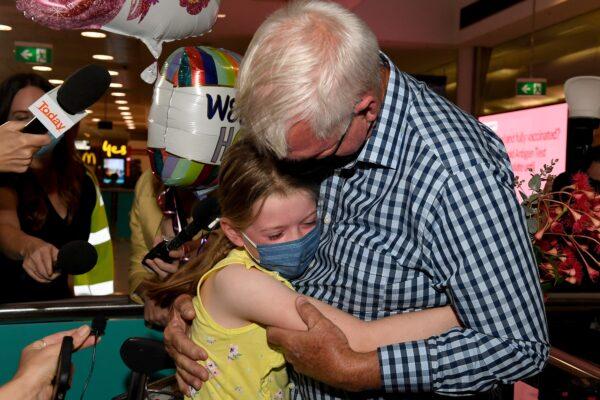 A man hugs his granddaughter Charlotte Roempke upon arriving at Sydney International Airport in Sydney, Australia, on Feb. 21, 2022. (Saeed Khan/AFP via Getty Images)
