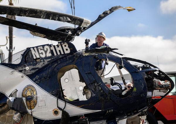 A crane is used to lift a Huntington Beach Police helicopter out of the water in Newport Beach, Calif., on Feb. 20, 2022. Officer Nicholas Vella, a 14-year veteran of the force, died in the accident. (Mindy Schauer/The Orange County Register via AP)