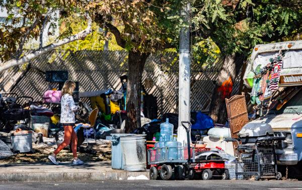 A woman walks past a homeless encampment in the Venice neighborhood in Los Angeles on Feb. 18, 2022. (John Fredricks/The Epoch Times)