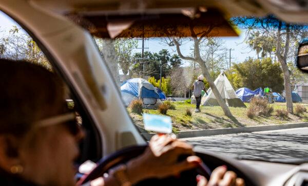 A Venice Beach resident drives past a homeless encampment in front of the Abbot Kinney Memorial Branch Library in Venice, Calif., on Feb. 18, 2022. (John Fredricks/The Epoch Times)