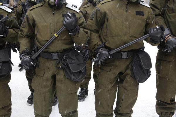 Canadian police in helmets and carrying long batons near Parliament Hill in Ottawa on Feb. 20, 2022. (Richard Moore/The Epoch Times)