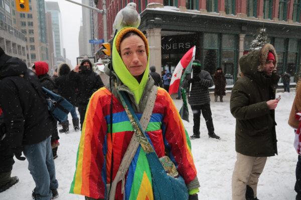 Protest supporter Andrea Gosselin, from Ontario, with her friend Little Cloud the pigeon in front of the police line near Parliament Hill, Ottawa, on Feb. 20, 2022. (Richard Moore/The Epoch Times)