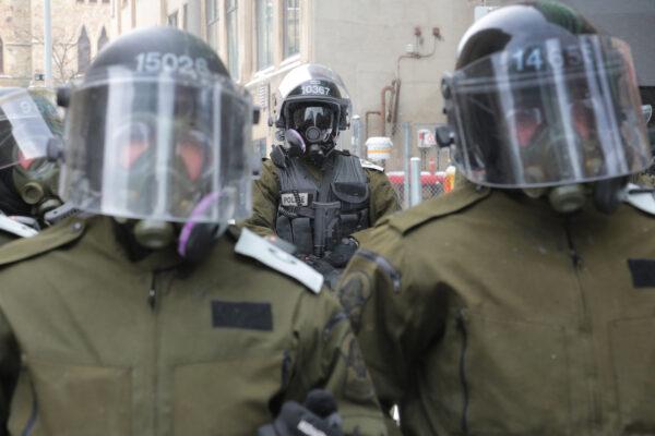 Canadian police watch protesters near Parliament Hill in Ottawa on Feb. 20, 2022. (Richard Moore/The Epoch Times)
