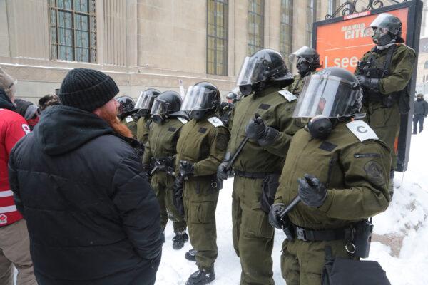 Protesters stare at a line of police near Parliament Hill in the Canadian capital of Ottawa on Feb. 20, 2022. (Richard Moore/The Epoch Times)