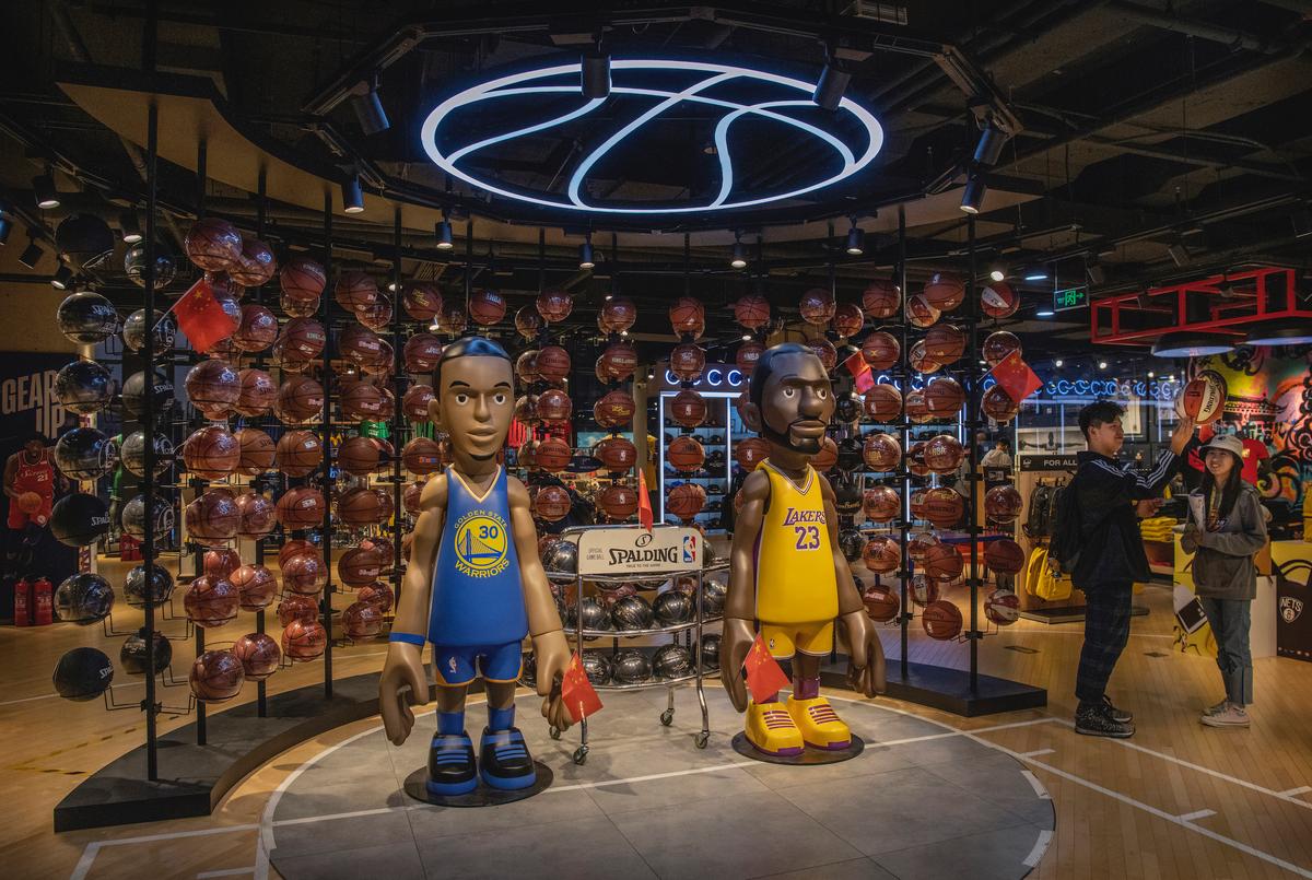 A Chinese couple play with a ball next to a display set up in the NBA retail store in Beijing, on Oct. 9, 2019. (Kevin Frayer/Getty Images)