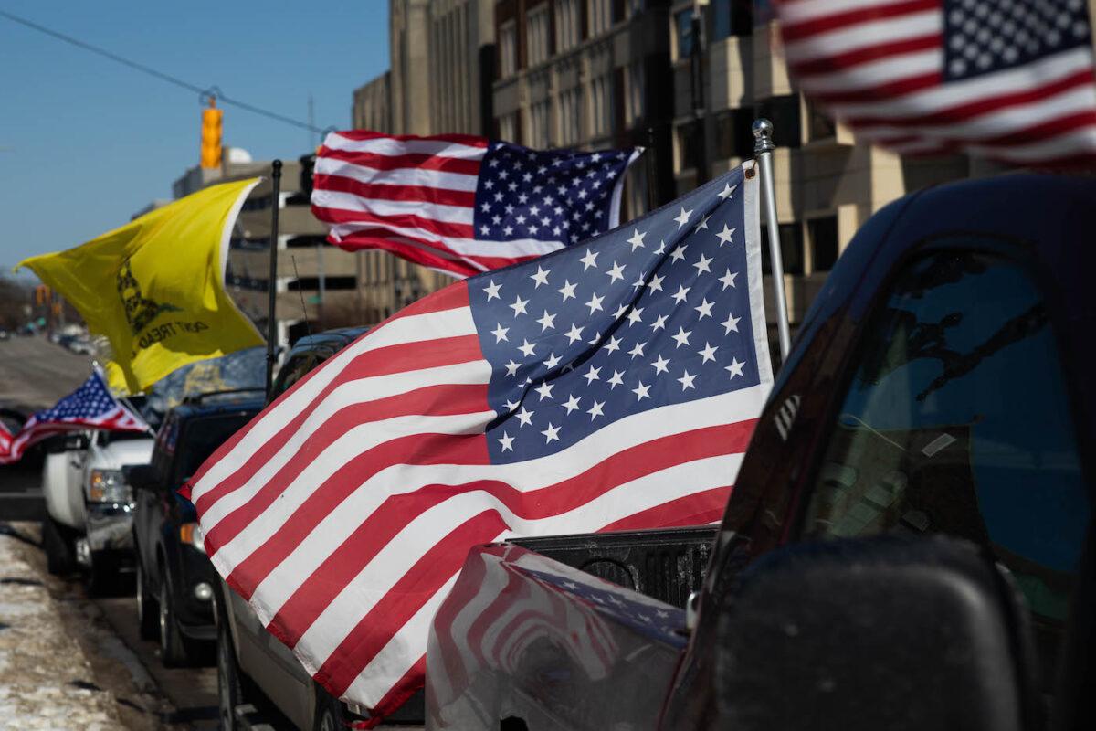 American flags blow in the wind as cars line up to participate in a Freedom Convoy in Lansing, Michigan, on Feb. 20, 2022. (Emily Elconin/Getty Images)