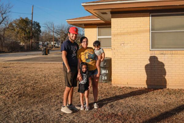Roman Rosas and Lyna Salazar with their children Adalynn and Joshuaa stand outside their home, which was hit by a truck during a high-speed chase in Brackettville, Texas, on Feb. 18, 2022. (Charlotte Cuthbertson/The Epoch Times)