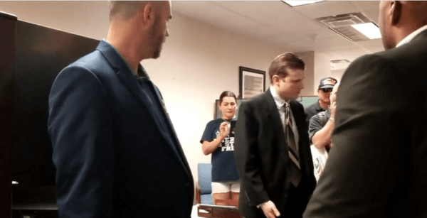 Screenshot from video showing the Aide to Florida State Rep. Chuck Brannan, surrounded by gun rights activists who want to know why he threw their petitions in the trash. (Courtesy of Matt Collins)
