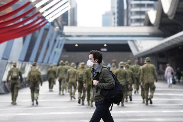 A man wearing a face mask walks past as the Australian Defence Force walk through the city in Melbourne, Australia, on July 27, 2020. (Quinn Rooney/Getty Images)