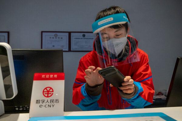 A worker at the front desk of Prince Ski Town Hotel checks a phone behind a sign saying "digital yuan (e-CNY) is accepted" in Zhangjiakou, China, on Dec. 4, 2021. (Andrea Verdelli/Getty Images)