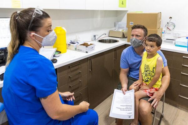 Registered nurse Emma Ahearn talks to Stephen Delaney ahead of his son Lachlan Delany receiving his COVID-19 vaccine in Sydney, Australia, on Jan. 11, 2022. (Jenny Evans/Getty Images)