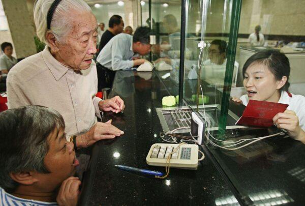 Chen Xiangying (L), 92, draws her first pension at a bank on Sept. 28, 2006, in Shanghai, China. (China Photos/Getty Images)