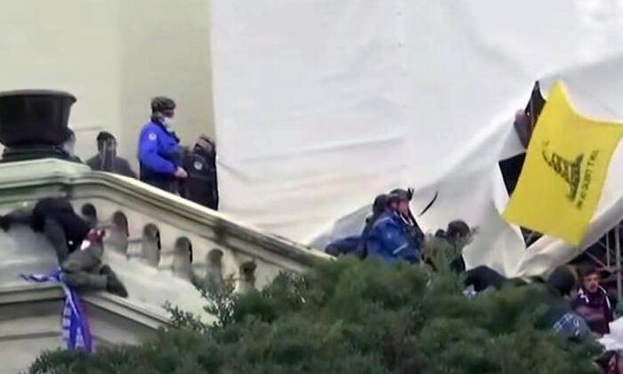 Guy Wesley Reffitt descending the West Terrace stairs at the U.S. Capitol on Jan. 6, 2021. On the ledge at left is Derrick Vargo, who says a police officer pushed him off the 20-foot-high wall seconds later. (U.S. Department of Justice/Screenshot via The Epoch Times)
