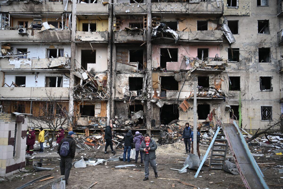 People gather in front of a damaged residential building at Koshytsa Street, a suburb of the Ukrainian capital Kyiv, where a military shell allegedly hit, on Feb. 25, 2022. (Daniel Leal/AFP via Getty Images)