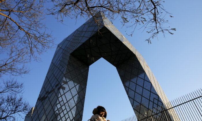 A morning commuter walks in front of the China Central Television (CCTV) building in Beijing, China, on Dec. 2, 2015. (Damir Sagolj/Reuters)