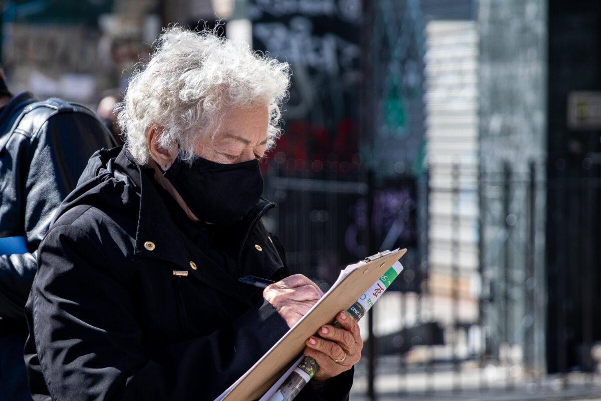 Bystanders sign a petition near a parade supporting the withdrawal of 390 million people from the Chinese Communist Party and its associate groups, in Brooklyn, N.Y., on Feb. 27, 2022. (Chung I Ho/The Epoch Times)