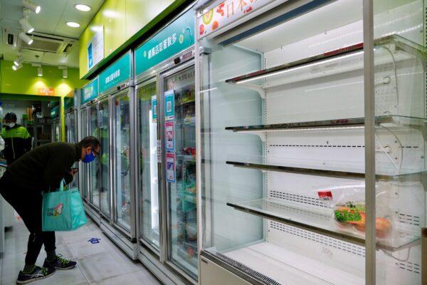A man looks for food next to the empty shelves of fruit as residents fear a fresh food shortage at a market in Hong Kong, on Feb. 28, 2022. (Vincent Yu/AP Photo)