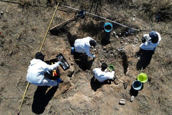 Forensic technicians excavate a field on a plot of land referred to as a cartel "extermination site" where burned human remains are buried, on the outskirts of Nuevo Laredo, Mexico, on Feb. 8, 2022. (Marco Ugarte/AP Photo)