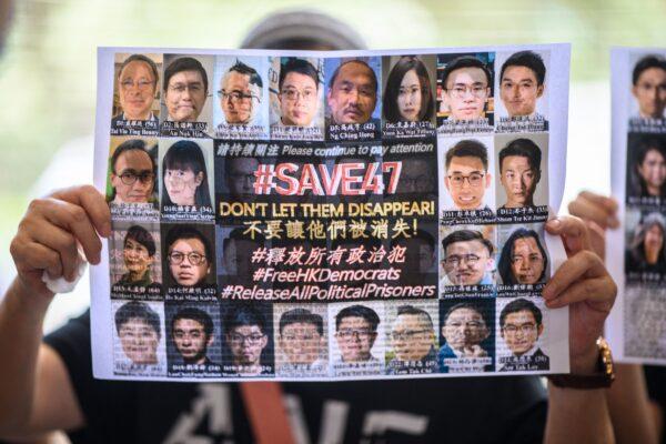 A supporter holds a poster showing some of the 47 pro-democracy activists on trial at the West Kowloon Court in Hong Kong on July 8, 2021, on charges of conspiracy to commit subversion under the national security law for taking part in unauthorised pro-democracy primaries in July 2020. (Anthony Kwan/AFP via Getty Images)