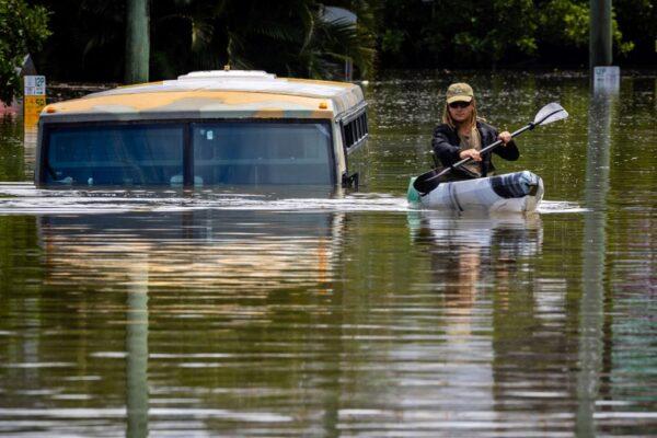 A man paddles his kayak next to a submerged bus on a flooded street in the town of Milton in suburban Brisbane, Australia, on Feb. 28, 2022. (Patrick Hamilton/AFP /AFP via Getty Images)
