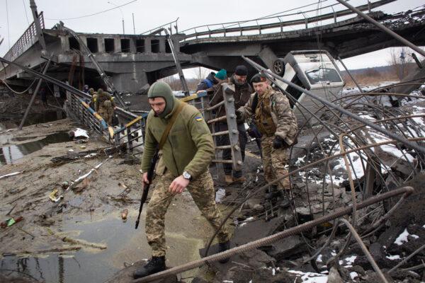 Ukrainian service members cross a destroyed bridge in Irpin, Ukraine, on March 1, 2022. (Anastasia Vlasova/Getty Images)