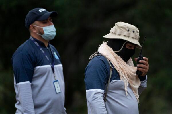Jorge Macias (R), head of the Tamaulipas state search commission, uses a two-way radio while walking on a field on the outskirts of Ciudad Victoria, Mexico on Feb. 3, 2022. (Marco Ugarte/AP Photo)