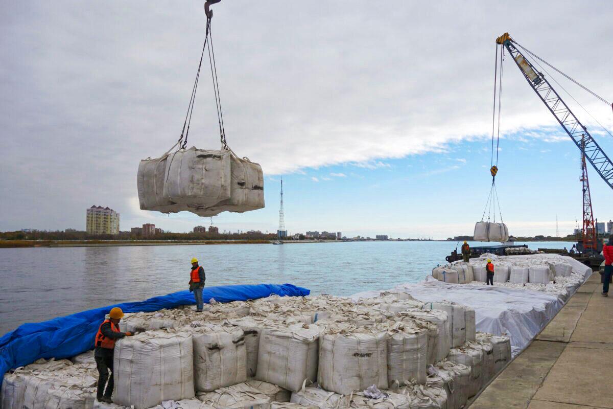 Workers stand near a crane unloading sacks of imported soybeans from Russia at Heihe port in Heilongjiang Province, China, on Oct. 10, 2018. (Stringer/Reuters)