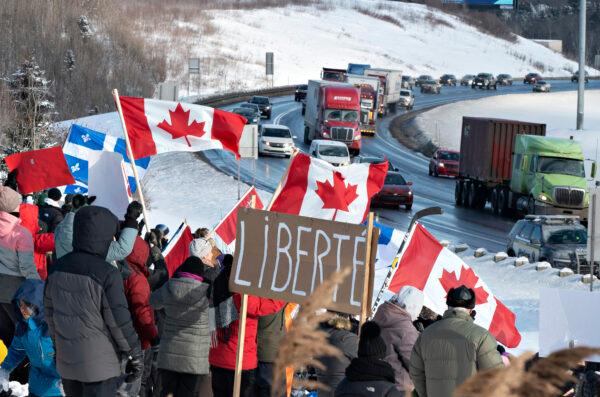 Hundreds of people gather by TransCanada Highway 20 to show their support to truckers heading to Ottawa to protest against COVID-19 restrictions in Levis, Quebec, on Jan. 28, 2022. (Jacques Boissinot/The Canadian Press)