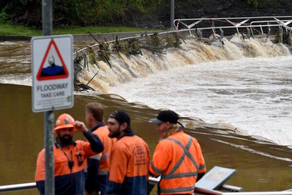 Construction workers watch the overflowing Parramatta river in Sydney, Australia, on March 3, 2022. (Saeed Khan/AFP via Getty Images)