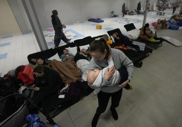 A woman comforts her baby at a temporary shelter set up in a market hall for displaced persons fleeing Ukraine, in Przemysl, Poland, March 3, 2022. (The Canadian Press/Czarek Sokolowski)