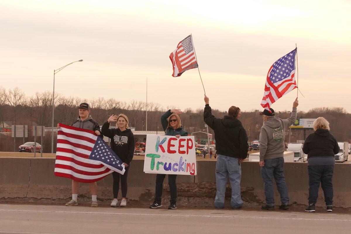 People hold signs at an overpass in support of t+he People's Convoy, in Missouri, on Feb. 28, 2022. (Enrico Trigoso/The Epoch Times)