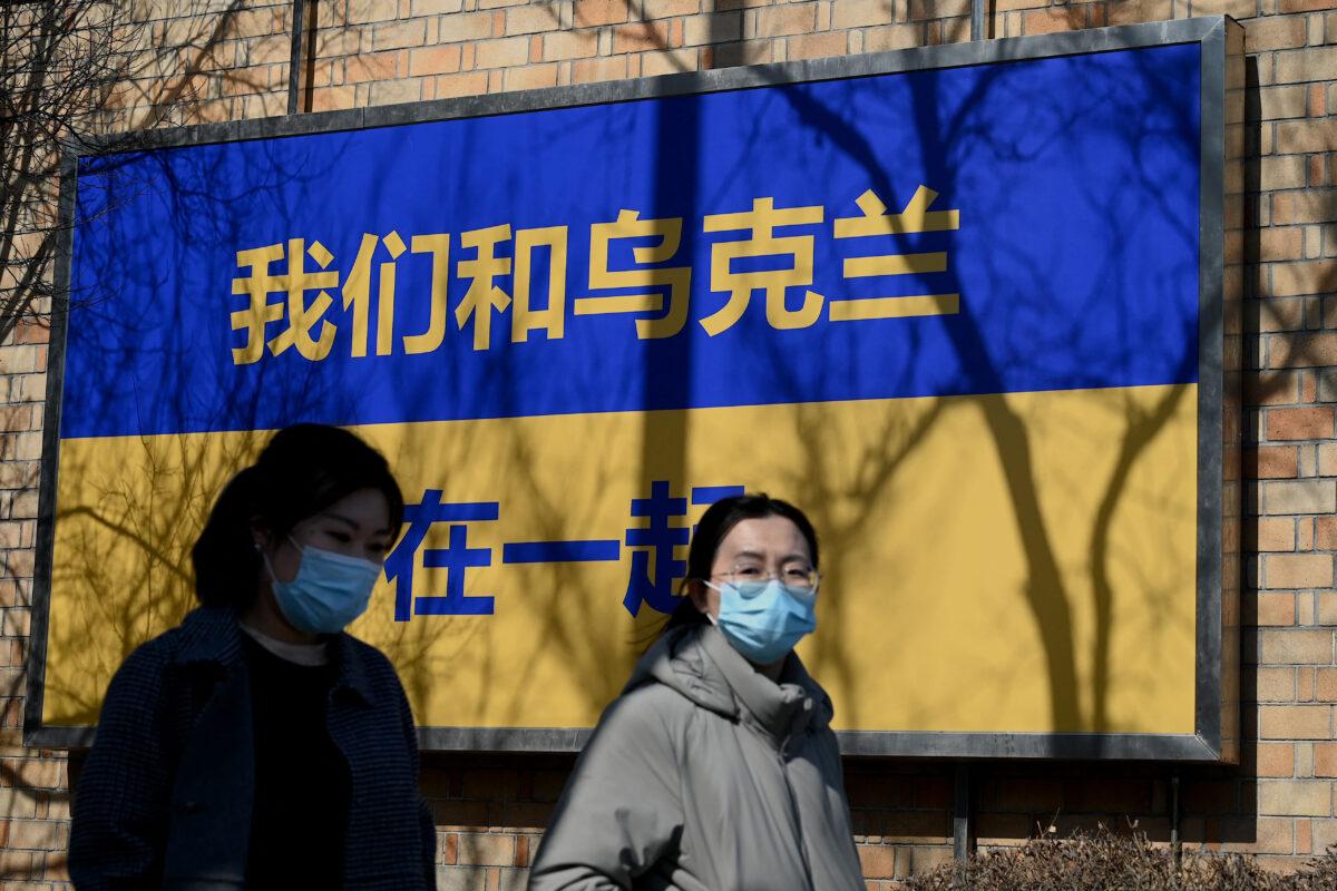 People walk past signage in the design of Ukraine's national flag with the message "We Support Ukraine" outside the Canadian Embassy in Beijing on March 3, 2022. (Noel Celis/AFP via Getty Images)