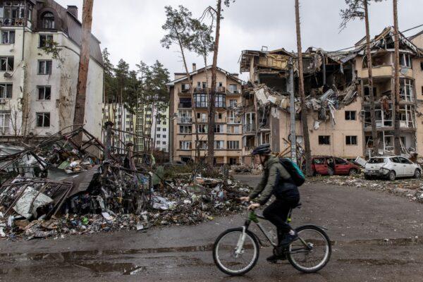 A man rides his bike past destroyed buildings in Irpin, Ukraine, on March 3, 2022, as Russia continues its assault on Ukraine's major cities, including the capital Kyiv. (Chris McGrath/Getty Images)