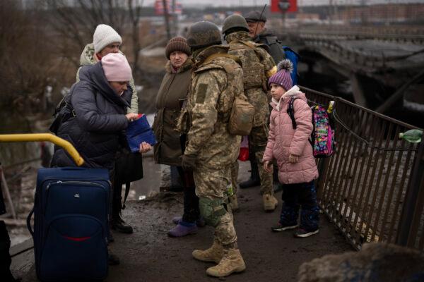 Ukrainian soldiers check people's identity cards as they flee their neighborhoods, on the outskirts of Kyiv, Ukraine, on March 2. 2022. (Emilio Morenatti/AP Photo)