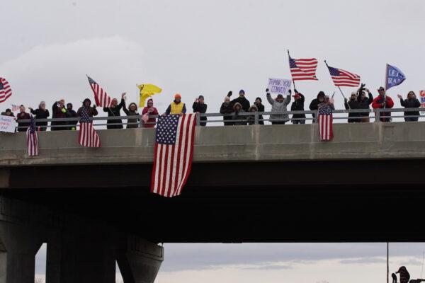 Supporters wave U.S. flags from an overpass in support of The People's Convoy traveling from Indiana to Lore City, Ohio, on March 3, 2022. (Enrico Trigoso/The Epoch Times)