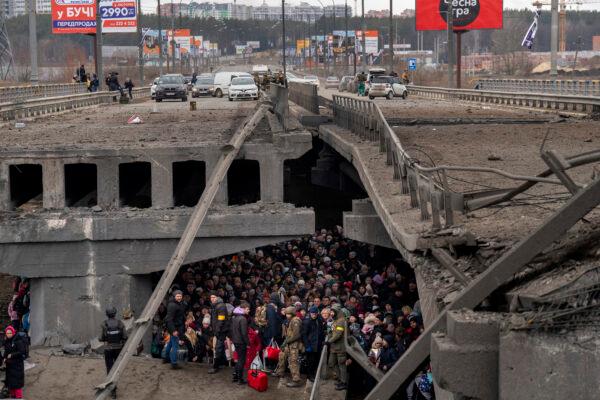 Ukrainians crowd under a destroyed bridge as they try to flee crossing the Irpin river in the outskirts of Kyiv, Ukraine, on March 5, 2022. (Emilio Morenatti/AP)